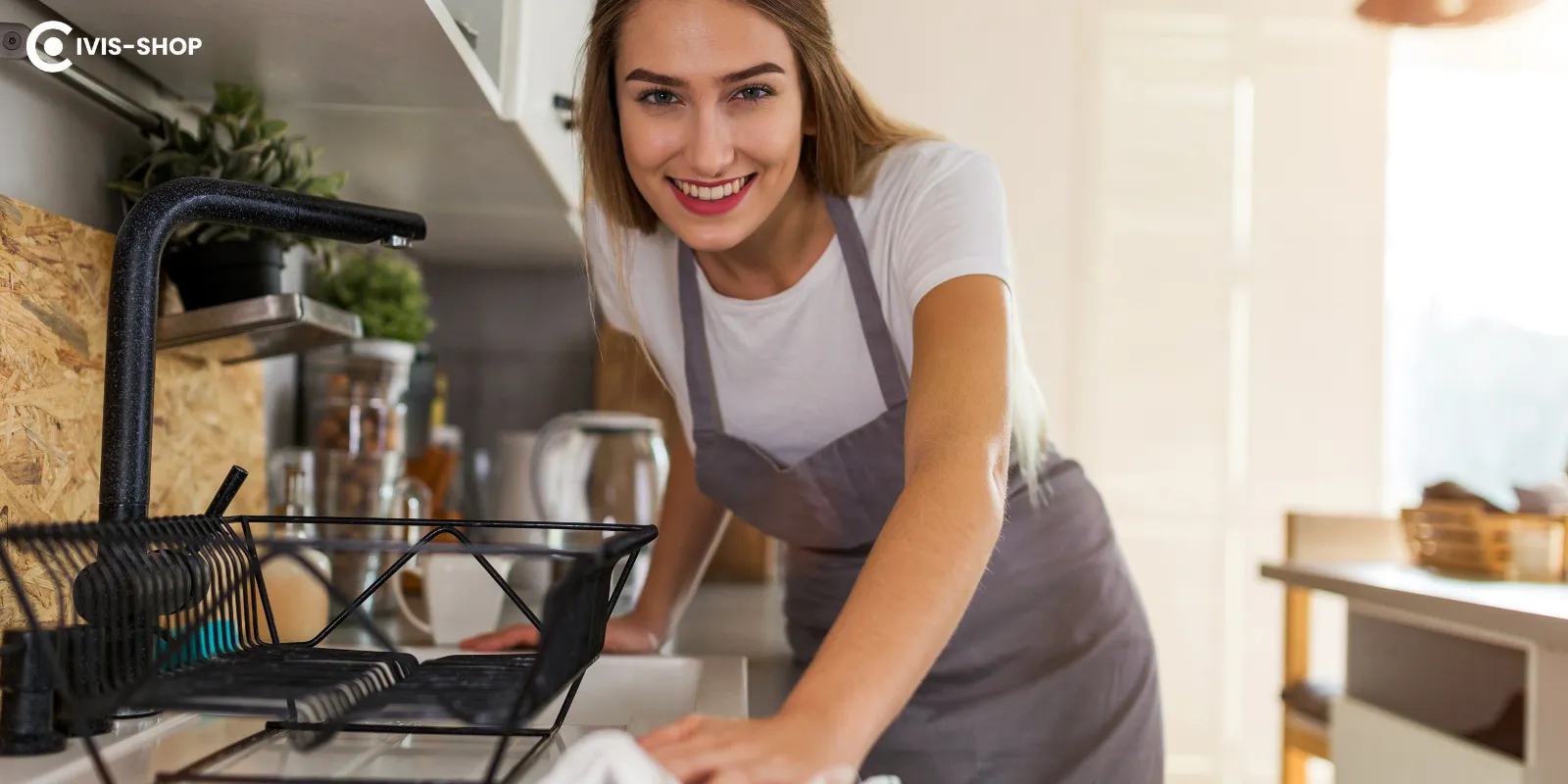 Egy mosolygós nő a konyhában a konyhai berendezések tisztítását végzi.